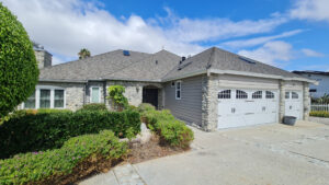 Front exterior of stone facade home with three-car garage photographed in San Diego