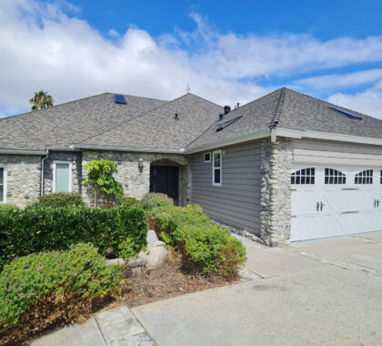 Front exterior of stone facade home with three-car garage photographed in San Diego